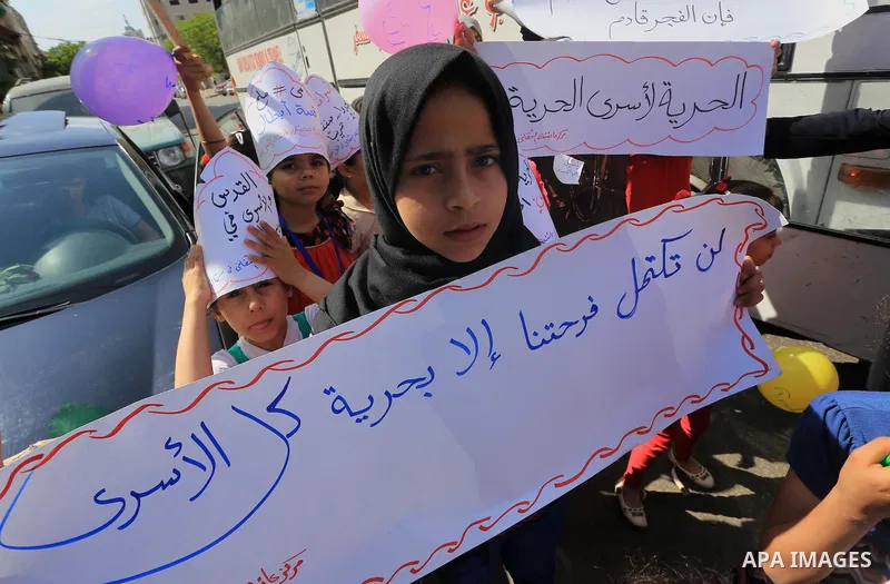 Palestinians hold pictures of prisoners held in Israeli jails, during a protest, in front of Red cross office, in Gaza city, on June 01, 2015. Photo by Mohammed Asad