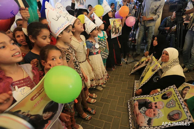 Palestinians hold pictures of prisoners held in Israeli jails, during a protest, in front of Red cross office, in Gaza city, on June 01, 2015. Photo by Mohammed Asad