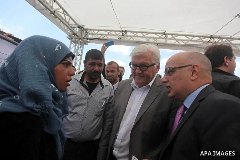 German Foreign Minister Frank-Walter Steinmeier speaks to a fisherwoman next to a destroyed rooms of Palestinian fishermen, damaged during Israeli Hamas conflict of 2014, in Gaza port, during his visit to Gaza City, 01 J...