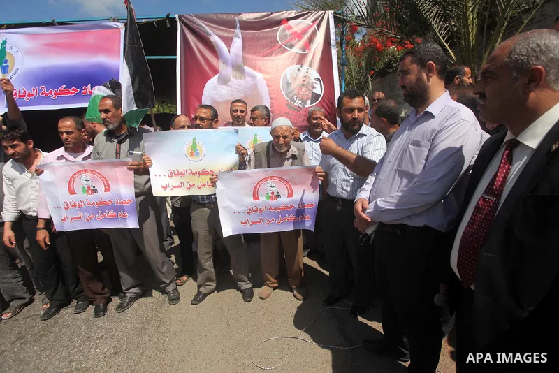 Palestinians take part in a protest marking the first anniversary of the Palestinian national unity government, in front of the headquarters of the Council of Ministers, in Gaza city on June 2, 2015. Photo by Ashraf Amra