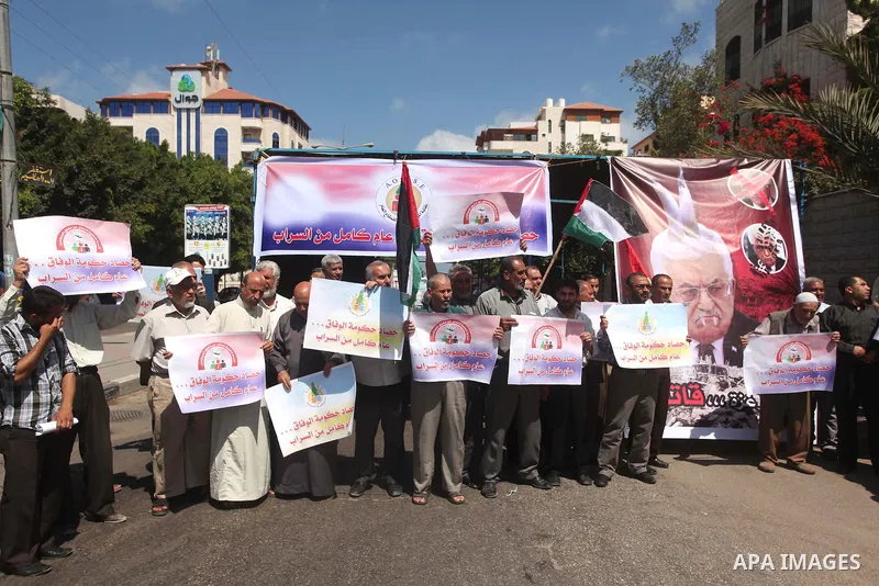 Palestinians take part in a protest marking the first anniversary of the Palestinian national unity government, in front of the headquarters of the Council of Ministers, in Gaza city on June 2, 2015. Photo by Ashraf Amra
