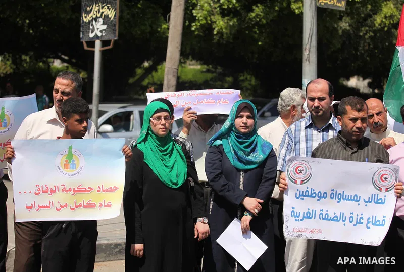 Palestinians take part in a protest marking the first anniversary of the Palestinian national unity government, in front of the headquarters of the Council of Ministers, in Gaza city on June 2, 2015. Photo by Ashraf Amra