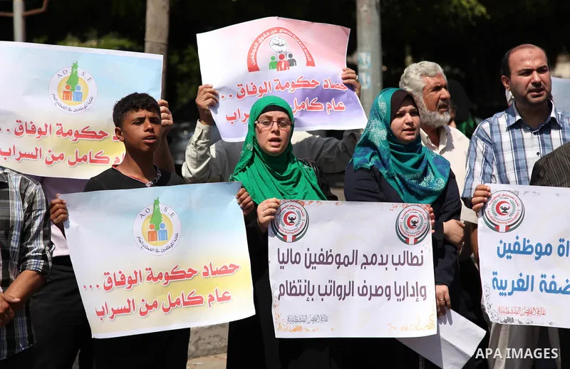 Palestinians take part in a protest marking the first anniversary of the Palestinian national unity government, in front of the headquarters of the Council of Ministers, in Gaza city on June 2, 2015. Photo by Ashraf Amra