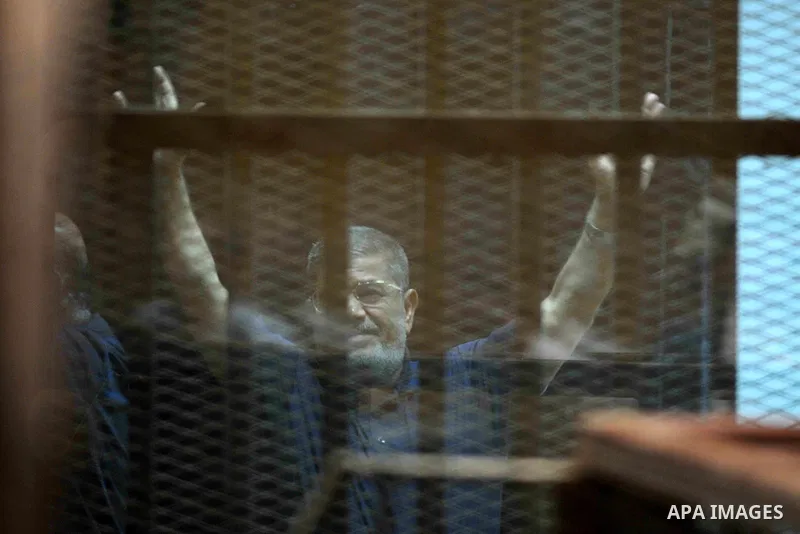 Ousted Egyptian president Mohamed Morsi gestures from the defendants cage as he attends his trial at the police academy on the outskirts of the capital Cairo on June 2, 2015. The Egyptian court postponed its final ruling...