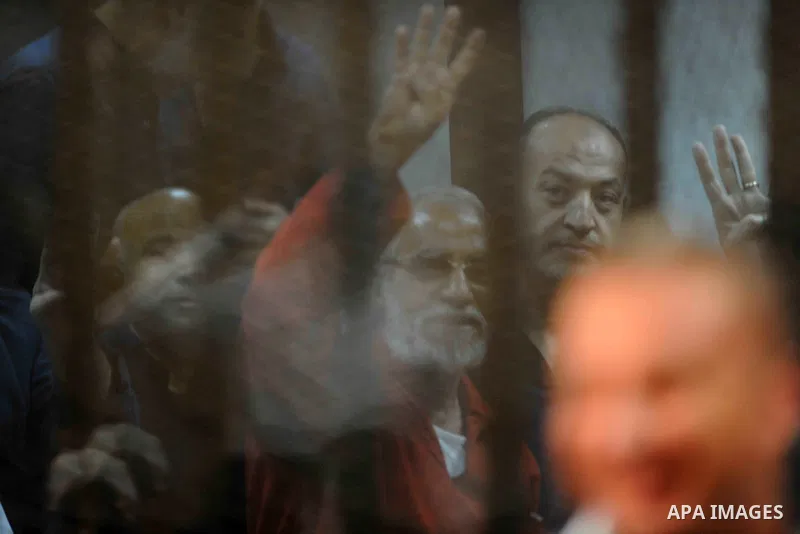 Muslim Brotherhood's Supreme Guide Mohamed Badie waves with the Rabaa sign, symbolizing support for the Muslim Brotherhood, with other brotherhood members at the police academy on the outskirts of the capital Cairo on Ju...