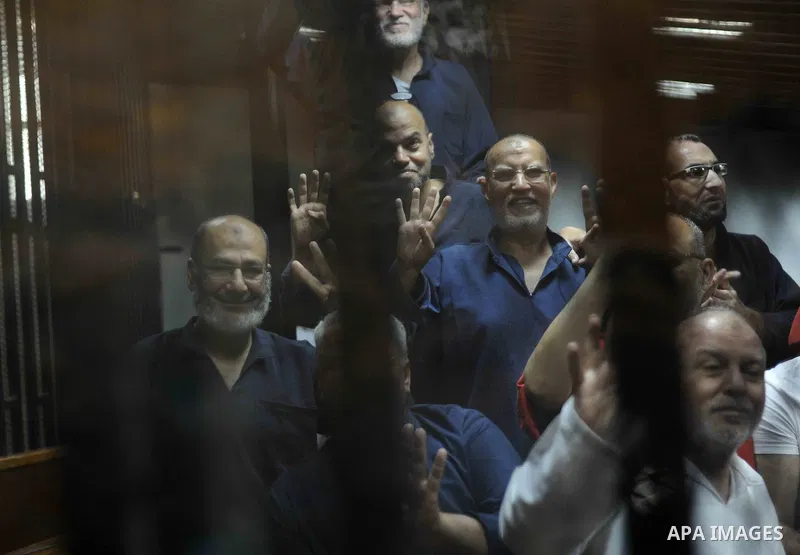 Muslim Brotherhood's Supreme Guide Mohamed Badie waves with the Rabaa sign, symbolizing support for the Muslim Brotherhood, with other brotherhood members at the police academy on the outskirts of the capital Cairo on Ju...