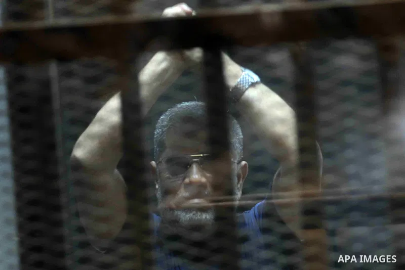 Ousted Egyptian president Mohamed Morsi gestures from the defendants cage as he attends his trial at the police academy on the outskirts of the capital Cairo on June 2, 2015. The Egyptian court postponed its final ruling...