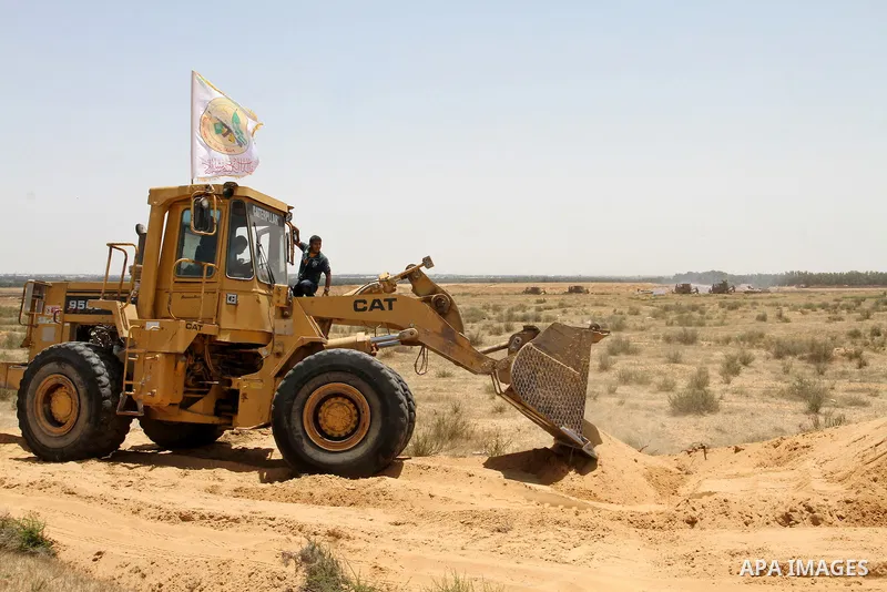 Palestinians rid a bulldozer in front of Israeli bulldozers working along a barbed wire fence that separates Rafah in the southern Gaza Strip and the Israeli border, on June 03, 2015. Israeli troops backed by military ve...