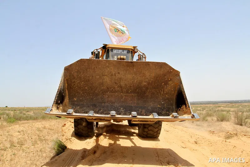 A Palestinian militant of the Ezzedine al-Qassam Brigades, Hamas' armed wing, rides a bulldozer in front of Israeli bulldozers working along a barbed wire fence that separates Rafah in the southern Gaza Strip and the Isr...