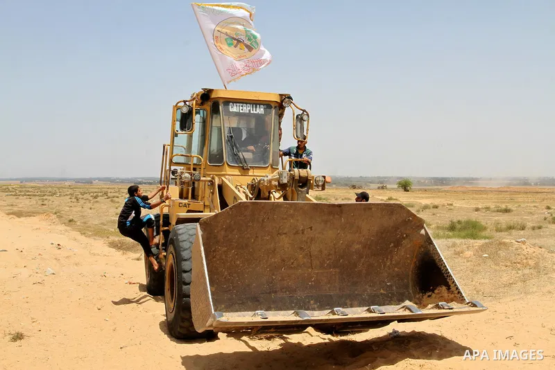 Palestinians rid a bulldozer in front of Israeli bulldozers working along a barbed wire fence that separates Rafah in the southern Gaza Strip and the Israeli border, on June 03, 2015. Israeli troops backed by military ve...