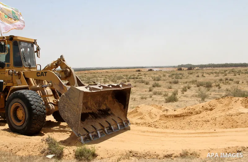 A Palestinian militant of the Ezzedine al-Qassam Brigades, Hamas' armed wing, rides a bulldozer in front of Israeli bulldozers working along a barbed wire fence that separates Rafah in the southern Gaza Strip and the Isr...