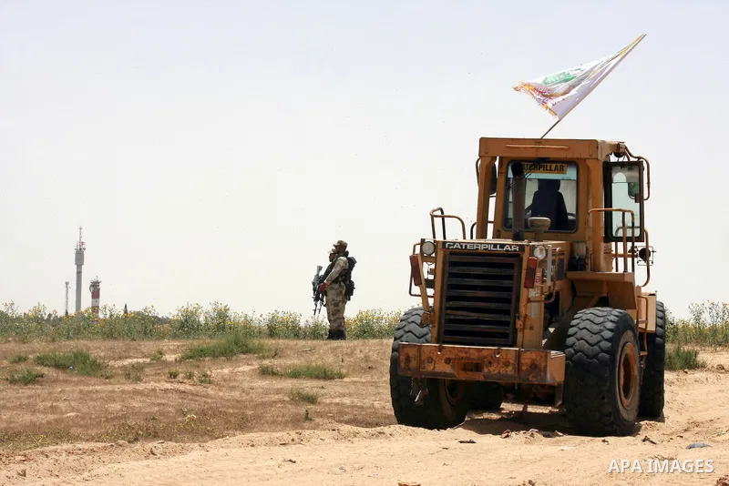 A Palestinian militant of the Ezzedine al-Qassam Brigades, Hamas' armed wing, rides a bulldozer in front of Israeli bulldozers working along a barbed wire fence that separates Rafah in the southern Gaza Strip and the Isr...