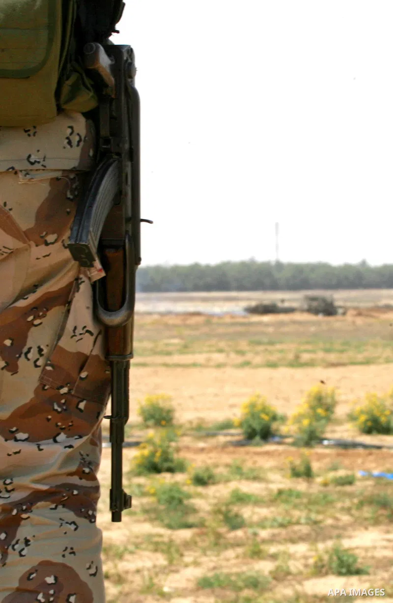 A Palestinian militant of the Ezzedine al-Qassam Brigades, Hamas' armed wing, watches as an Israeli bulldozer working along a barbed wire fence that separates Rafah in the southern Gaza Strip and the Israeli border, on J...