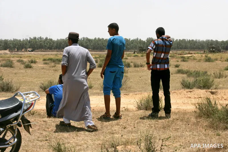 Palestinians watch Israeli bulldozers working along a barbed wire fence that separates Rafah in the southern Gaza Strip and the Israeli border, on June 03, 2015. Israeli troops backed by military vehicles and bulldozers...