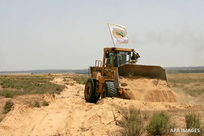 Palestinians rid a bulldozer in front of Israeli bulldozers working along a barbed wire fence that separates Rafah in the southern Gaza Strip and the Israeli border, on June 03, 2015. Israeli troops backed by military ve...