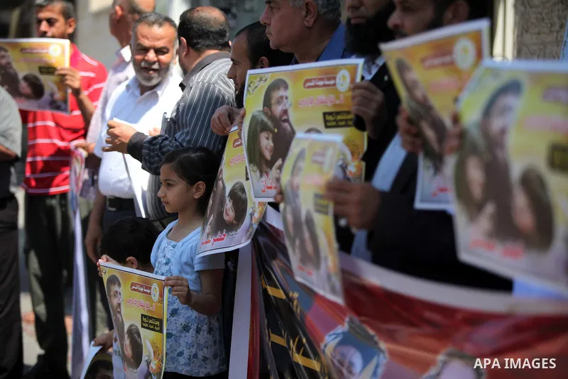 Palestinians holds a picture of Khader Adnan, a senior member of Islamic Jihad jailed in Israel, during a protest calling for the release of Adnan, in front of the red cross office in Gaza city, on June 4, 2015. Photo by...