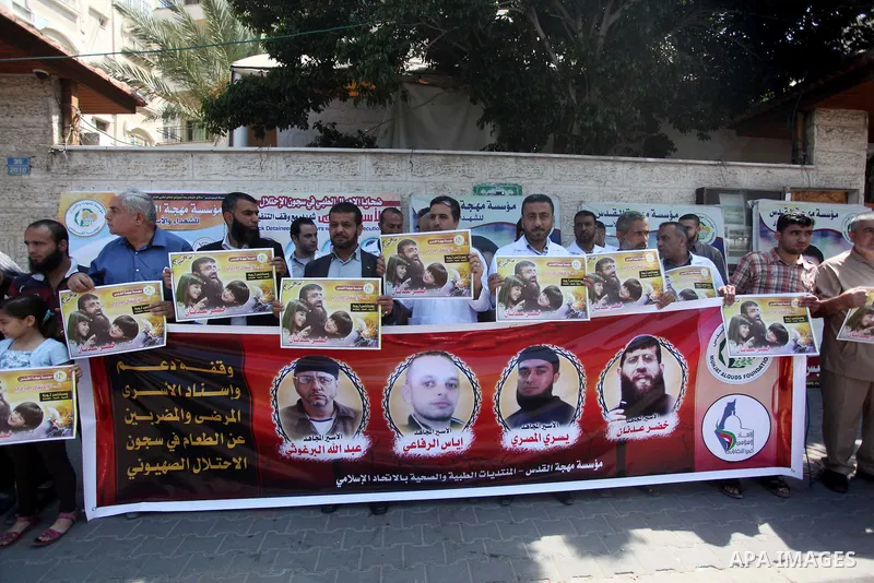 Palestinians holds a picture of Khader Adnan, a senior member of Islamic Jihad jailed in Israel, during a protest calling for the release of Adnan, in front of the red cross office in Gaza city, on June 4, 2015. Photo by...