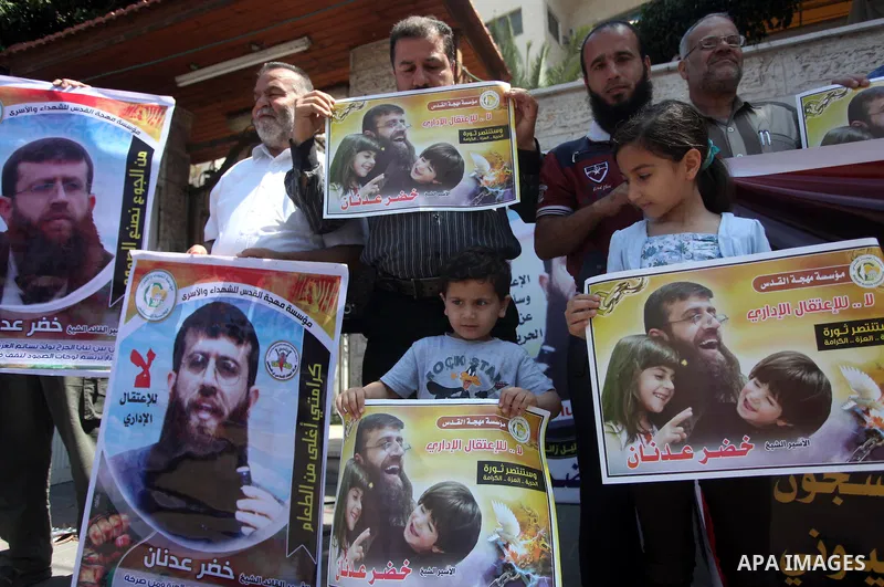 Palestinians holds a picture of Khader Adnan, a senior member of Islamic Jihad jailed in Israel, during a protest calling for the release of Adnan, in front of the red cross office in Gaza city, on June 4, 2015. Photo by...