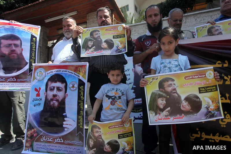 Palestinians holds a picture of Khader Adnan, a senior member of Islamic Jihad jailed in Israel, during a protest calling for the release of Adnan, in front of the red cross office in Gaza city, on June 4, 2015. Photo by...