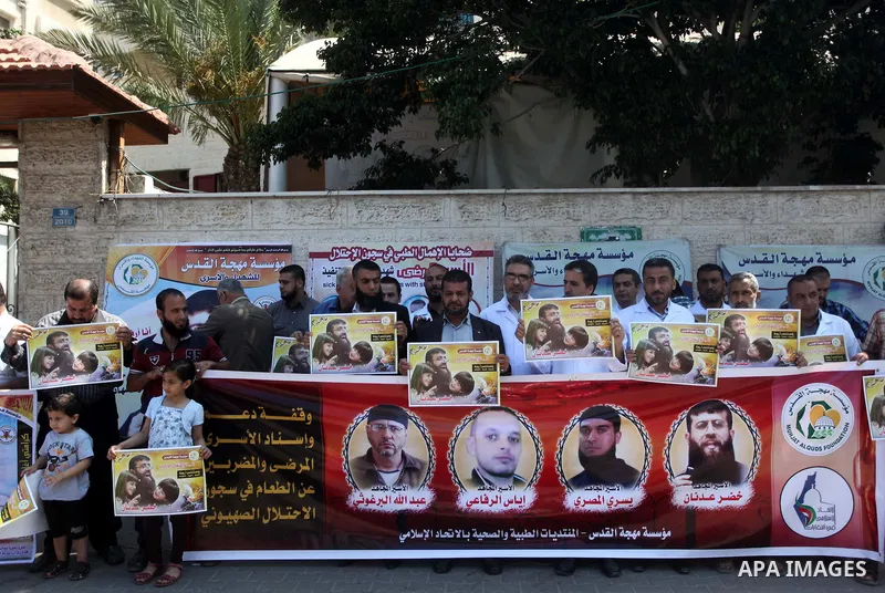 Palestinians holds a picture of Khader Adnan, a senior member of Islamic Jihad jailed in Israel, during a protest calling for the release of Adnan, in front of the red cross office in Gaza city, on June 4, 2015. Photo by...