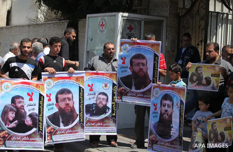 Palestinians holds a picture of Khader Adnan, a senior member of Islamic Jihad jailed in Israel, during a protest calling for the release of Adnan, in front of the red cross office in Gaza city, on June 4, 2015. Photo by...