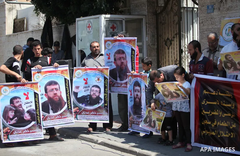 Palestinians holds a picture of Khader Adnan, a senior member of Islamic Jihad jailed in Israel, during a protest calling for the release of Adnan, in front of the red cross office in Gaza city, on June 4, 2015. Photo by...