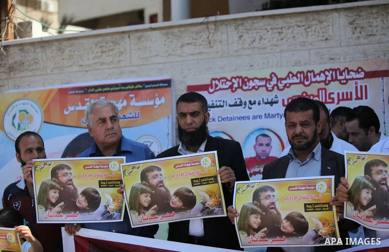 Palestinians holds a picture of Khader Adnan, a senior member of Islamic Jihad jailed in Israel, during a protest calling for the release of Adnan, in front of the red cross office in Gaza city, on June 4, 2015. Photo by...