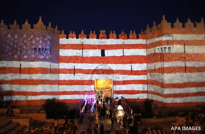 People watch an audiovisual light show projected over the ancient walls of Jerusalem's Damascus Gate in the old city during the Festival of Lights, on June 4, 2015. The festival is an annual event where thousands take pa...