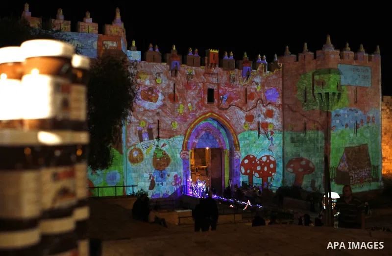 People watch an audiovisual light show projected over the ancient walls of Jerusalem's Damascus Gate in the old city during the Festival of Lights, on June 4, 2015. The festival is an annual event where thousands take pa...