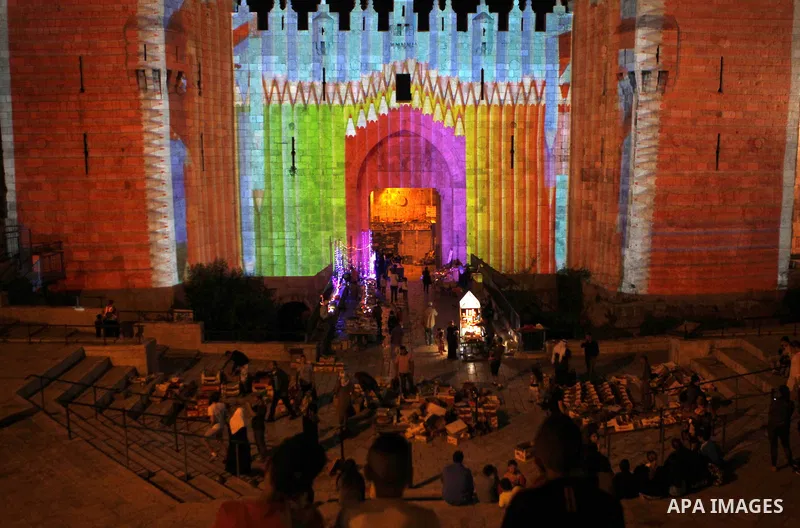 People watch an audiovisual light show projected over the ancient walls of Jerusalem's Damascus Gate in the old city during the Festival of Lights, on June 4, 2015. The festival is an annual event where thousands take pa...