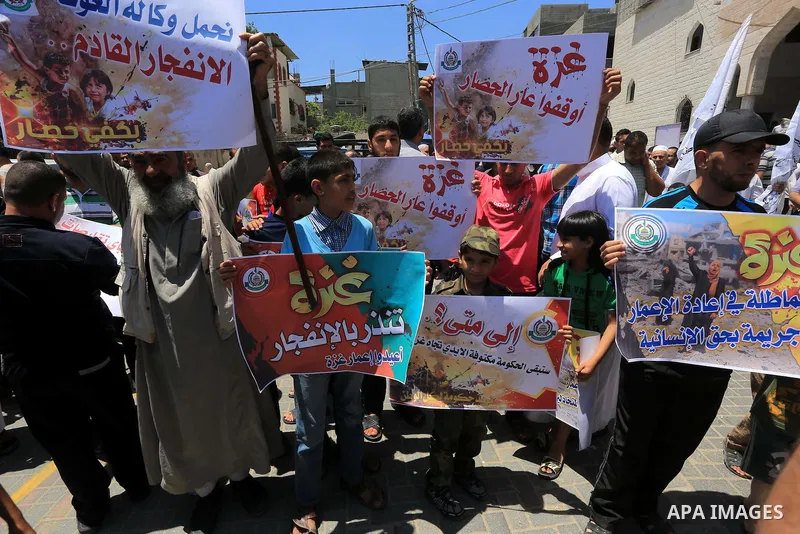 Palestinian children hold placards during a protest against the United Nations Relief and Works Agency (UNRWA) and the unity government, and calling for an acceleration in the reconstruction of homes destroyed during a 5...