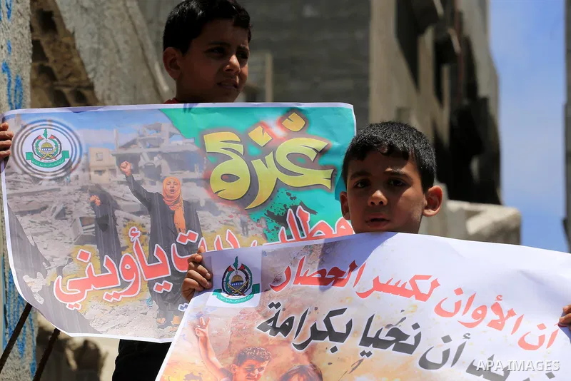 Palestinian children hold placards during a protest against the United Nations Relief and Works Agency (UNRWA) and the unity government, and calling for an acceleration in the reconstruction of homes destroyed during a 5...