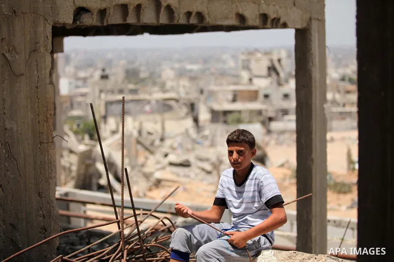 Palestinian boy sits on the rubble of houses which were destroyed during the 50-day war between Israel and Hamas militants in the summer of 2014, in the Al-Shaaf neighbourhood, on June 06, 2015. Qatar's ambassador Mohamm...