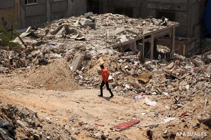 Palestinian man walk past the rubble of houses which were destroyed during the 50-day war between Israel and Hamas militants in the summer of 2014, in the Al-Shaaf neighbourhood, on June 06, 2015. Qatar's ambassador Moha...