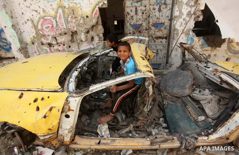 Palestinian boy sits inside damaged car which were destroyed during the 50-day war between Israel and Hamas militants in the summer of 2014, in the Al-Shaaf neighbourhood, on June 06, 2015. Qatar's ambassador Mohammed al...