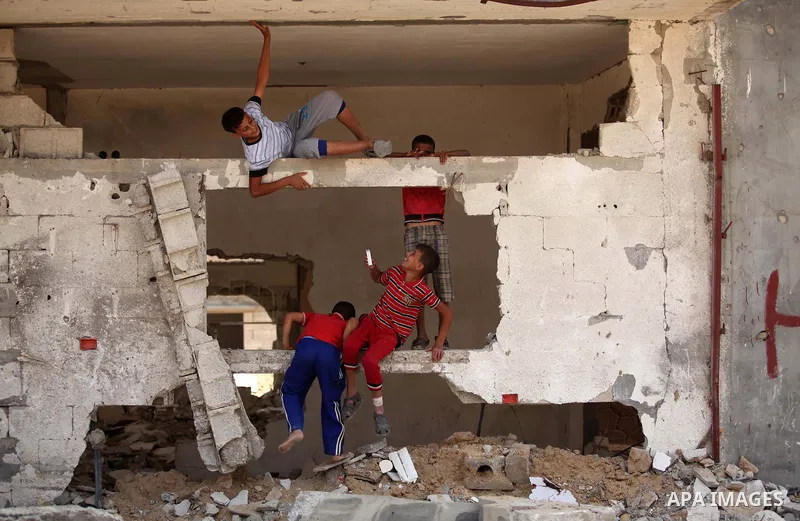 Palestinian children play on the rubble of houses which were destroyed during the 50-day war between Israel and Hamas militants in the summer of 2014, in the Al-Shaaf neighbourhood, on June 06, 2015. Qatar's ambassador M...