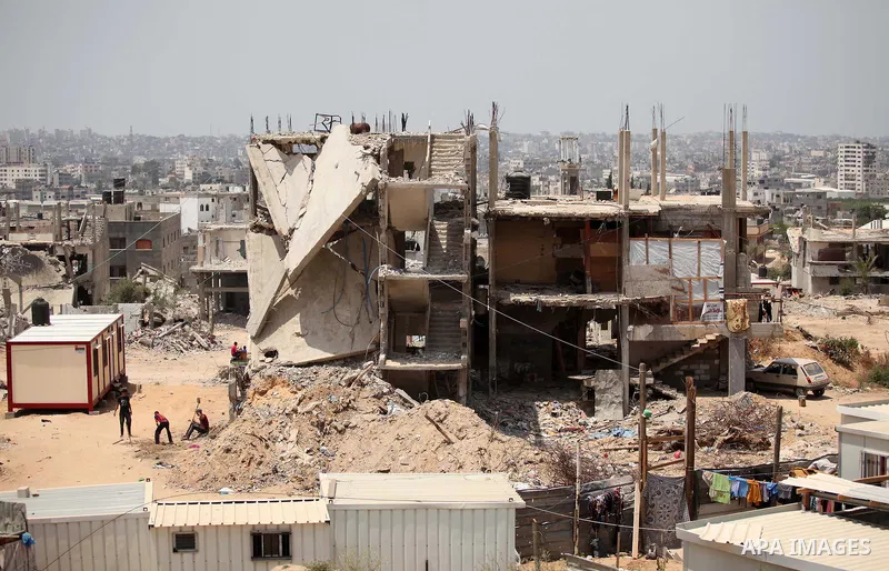 Palestinians sit on the rubble of houses which were destroyed during the 50-day war between Israel and Hamas militants in the summer of 2014, in the Al-Shaaf neighbourhood, on June 06, 2015. Qatar's ambassador Mohammed a...