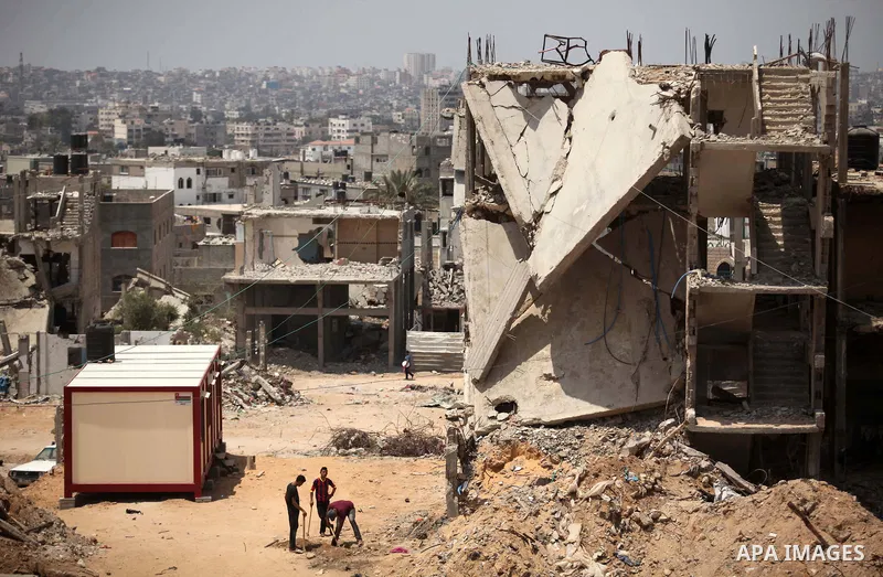 Palestinians sit on the rubble of houses which were destroyed during the 50-day war between Israel and Hamas militants in the summer of 2014, in the Al-Shaaf neighbourhood, on June 06, 2015. Qatar's ambassador Mohammed a...