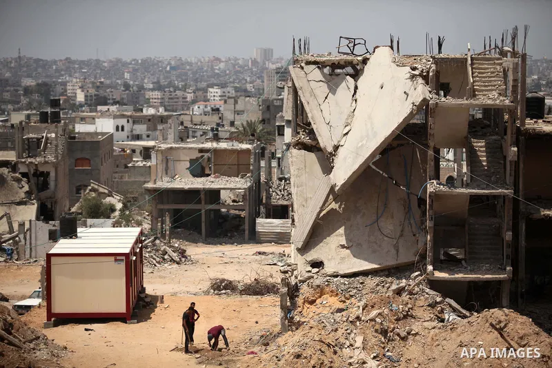 Palestinians sit on the rubble of houses which were destroyed during the 50-day war between Israel and Hamas militants in the summer of 2014, in the Al-Shaaf neighbourhood, on June 06, 2015. Qatar's ambassador Mohammed a...