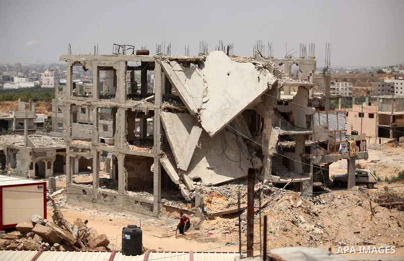 Palestinians sit on the rubble of houses which were destroyed during the 50-day war between Israel and Hamas militants in the summer of 2014, in the Al-Shaaf neighbourhood, on June 06, 2015. Qatar's ambassador Mohammed a...