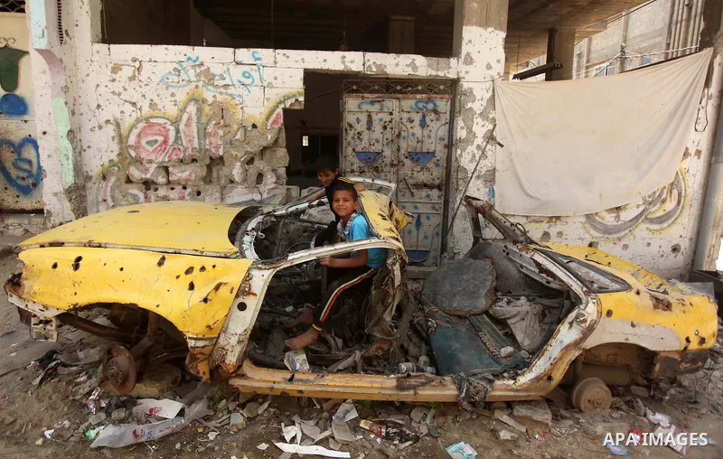 Palestinian boy sits inside damaged car which were destroyed during the 50-day war between Israel and Hamas militants in the summer of 2014, in the Al-Shaaf neighbourhood, on June 06, 2015. Qatar's ambassador Mohammed al...