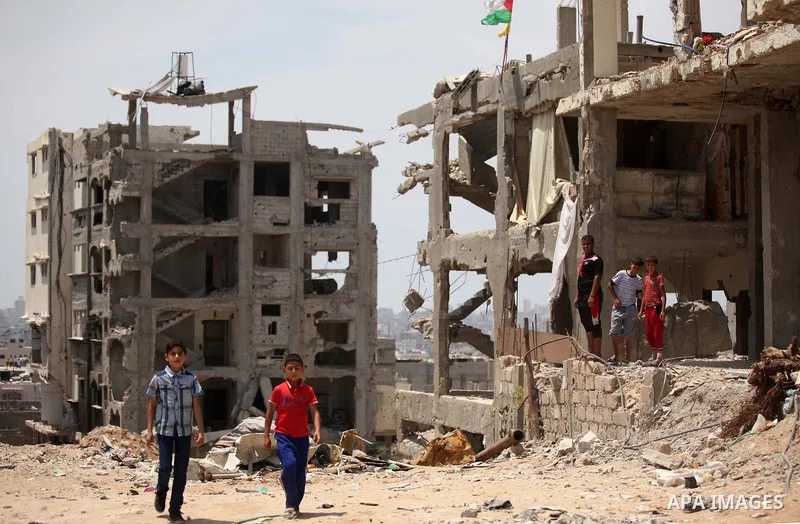 Palestinian children play on the rubble of houses which were destroyed during the 50-day war between Israel and Hamas militants in the summer of 2014, in the Al-Shaaf neighbourhood, on June 06, 2015. Qatar's ambassador M...