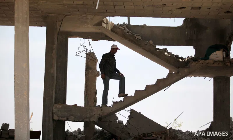 Palestinians sit on the rubble of houses which were destroyed during the 50-day war between Israel and Hamas militants in the summer of 2014, in the Al-Shaaf neighbourhood, on June 06, 2015. Qatar's ambassador Mohammed a...
