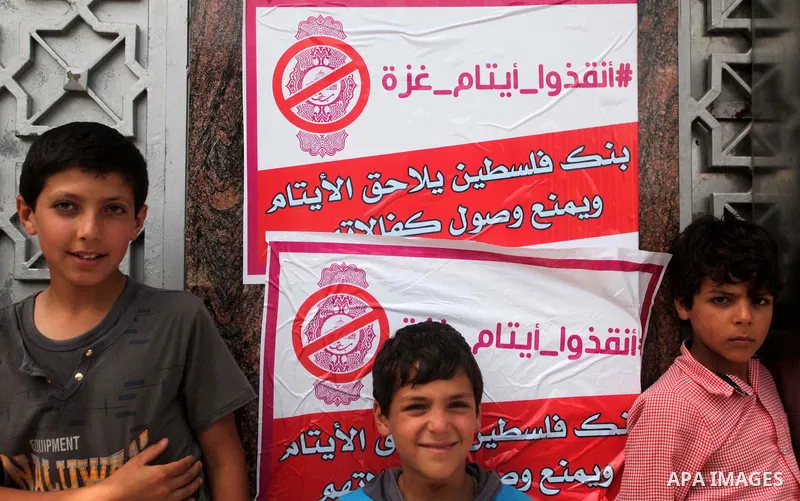 Palestinian orphans take part in a protest demanding their rights in front of Palestine Bank, in Gaza city on June 8, 2015. Photo by Ashraf Amra