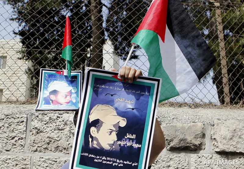 Palestinians hold placards during a demonstration in support of the family of Mohammed Abu Khder (portrait), a Palestinian teenager who was kidnapped from east Jerusalem on July 2,2014 and burned to death by Jewish extre...