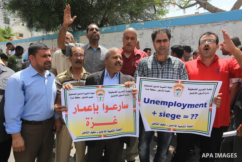 Palestinians hold banners during a protest against the UNRWA decision to reduce of the food aid in front of the headquarters United Nations Relief and Works Agency (UNRWA), in Gaza city, June 9, 2015. Photo by Mohammed A...