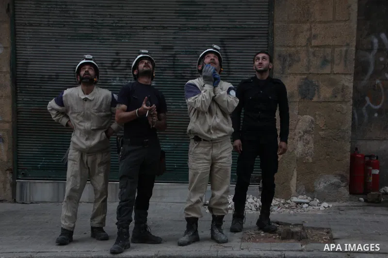 Rescue workers look on a building following a reported barrel bomb attack by Syrian government forces at al-mayser district in the northern Syrian city of Aleppo, June 8, 2015. Photo by Ameer al-Halbi