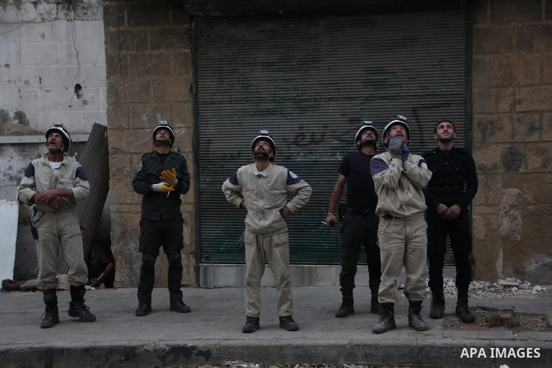 Rescue workers look on a building following a reported barrel bomb attack by Syrian government forces at al-mayser district in the northern Syrian city of Aleppo, June 8, 2015. Photo by Ameer al-Halbi