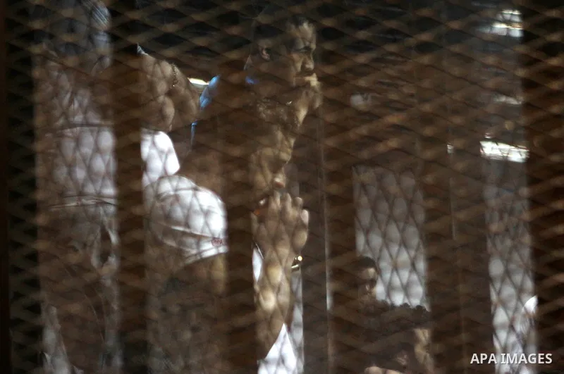 Egyptian defendants react behind bars after the verdict in their retrial over a 2012 stadium riot in the canal city of Port Said that left 74 people dead, in a court in the Egyptian capital, Cairo on June 9, 2015. The co...