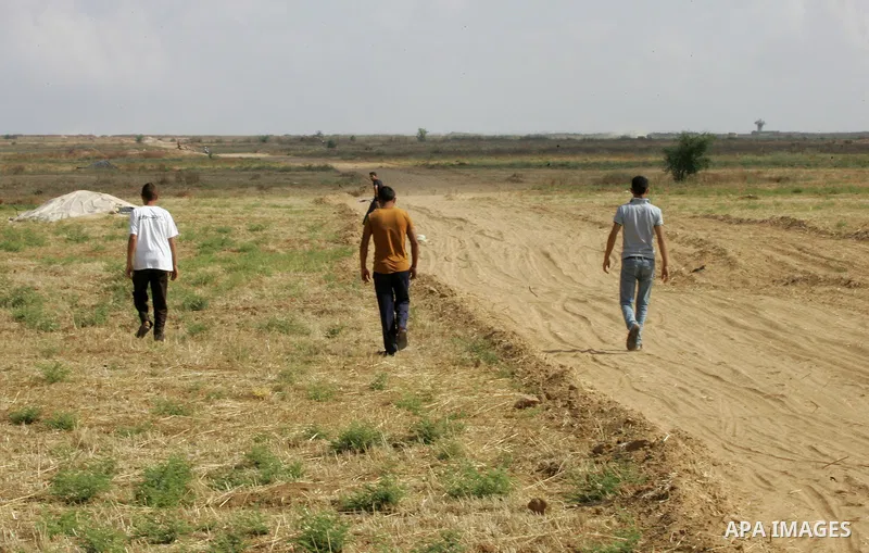 Palestinian men walk past the Israeli bulldozers working along a barbed wire fence that separates Khan Yunis in the southern Gaza Strip and the Israeli border, on June 10, 2015. Israel is to reopen border crossings to an...